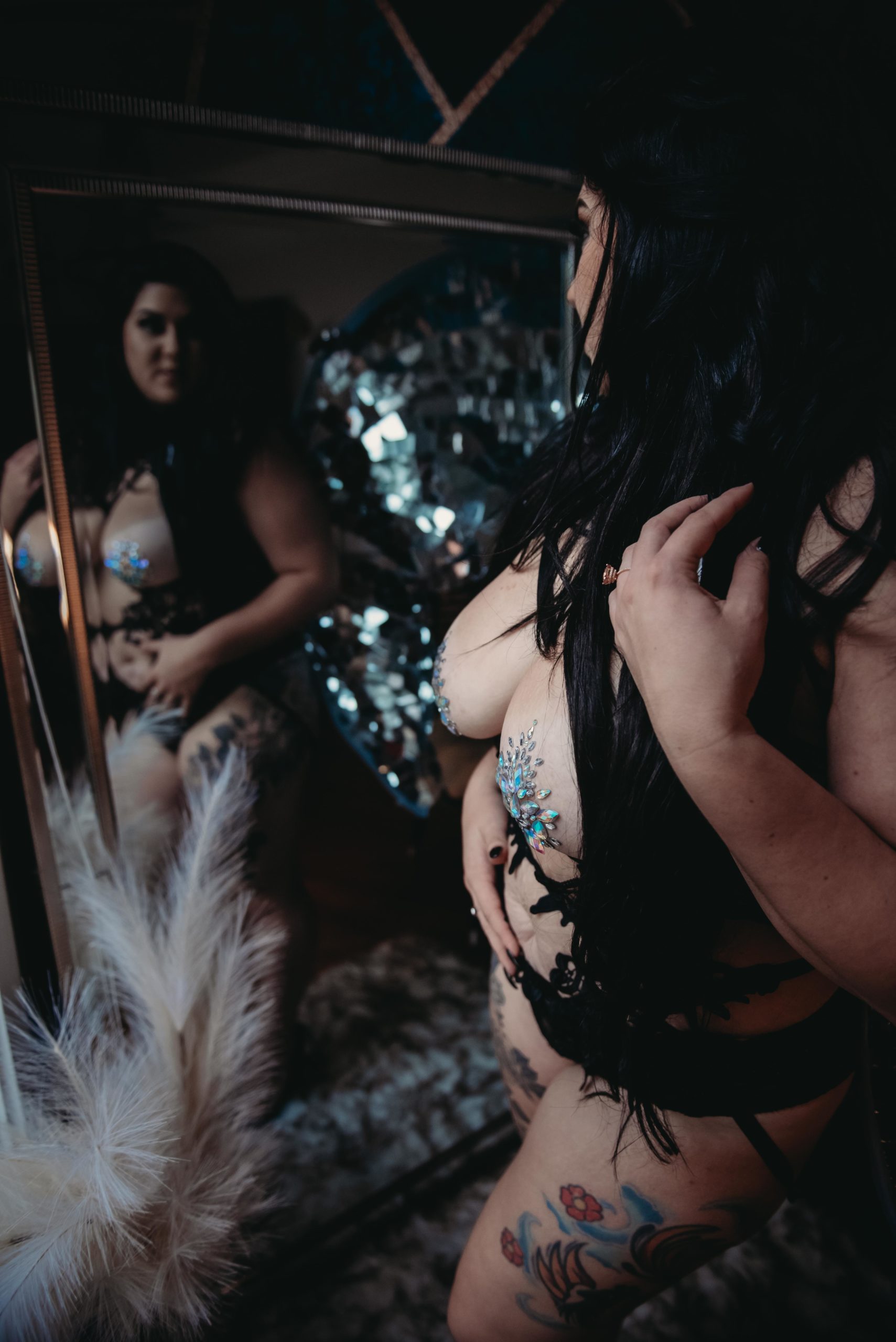 a woman posing in front of a mirror with butterfly wings in her boudoir session