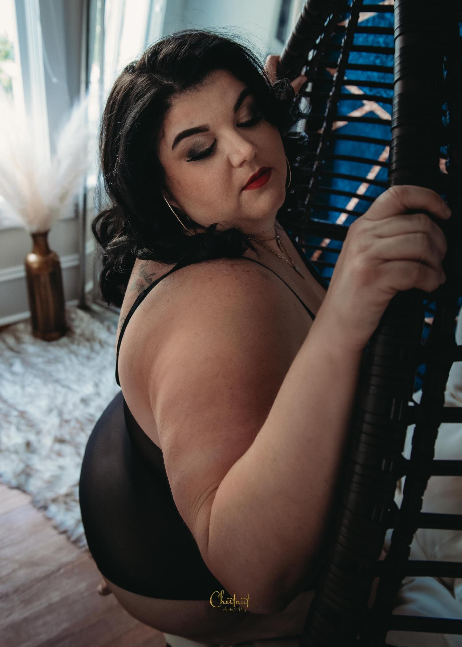 a woman posing in a chair during her boudoir photo shoot