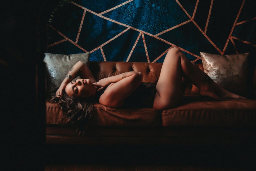 Elegant lounge scene with a person reclining on a tufted sofa against a striking geometric accent wall, illuminated with warm, atmospheric lighting.